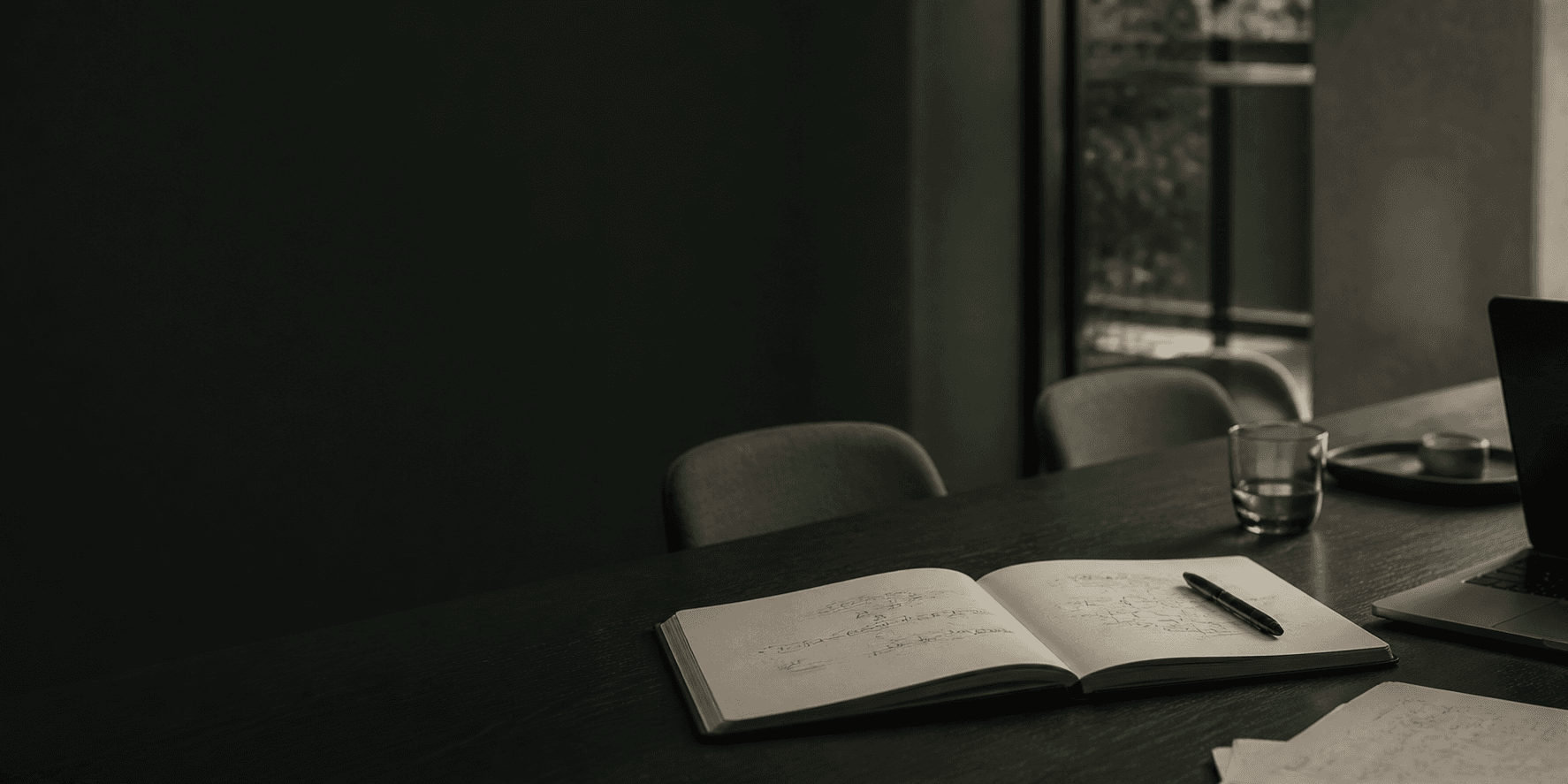 An open notebook and working materials on a conference table.